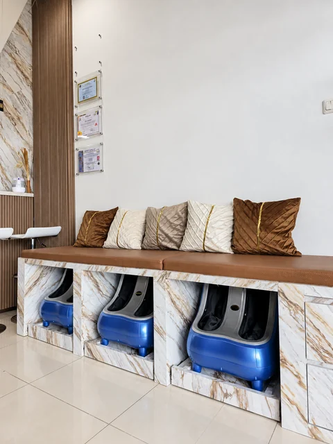 Bangku berlapis cokelat dengan lima bantal dan tiga alat pijat kaki di bawahnya.